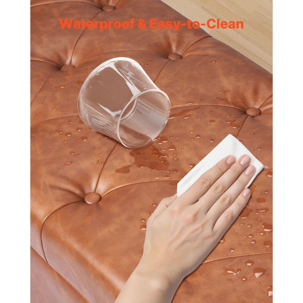 Close-up of a hand wiping water off the brown PU leather surface of the ottoman bench.