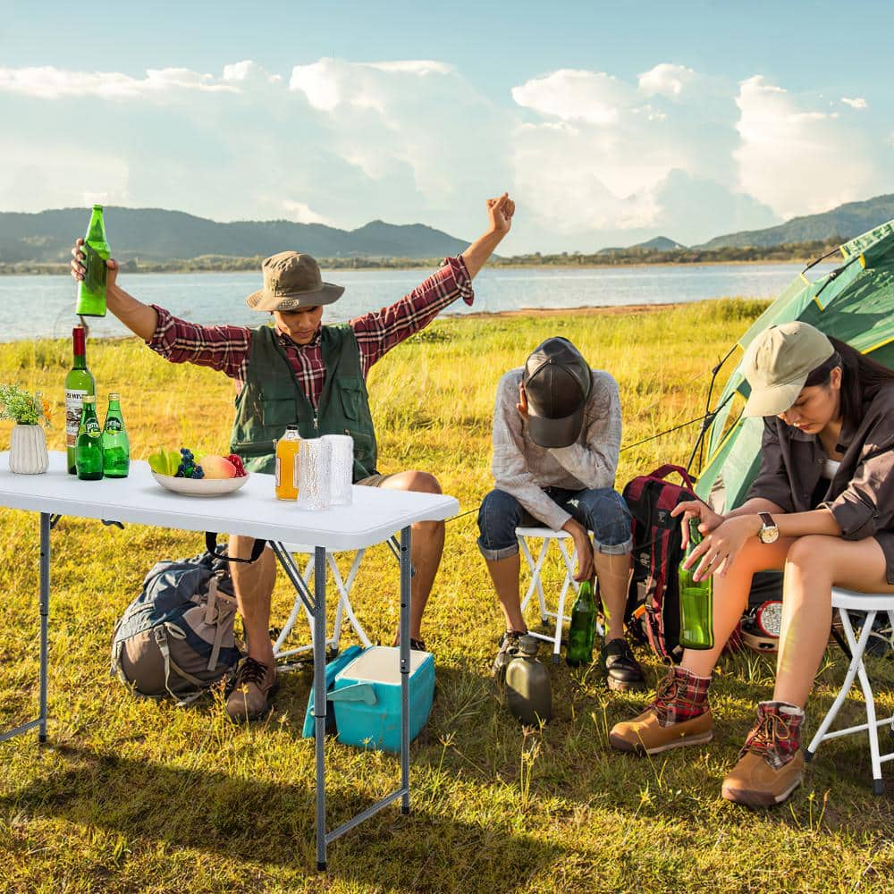 People using white folding stools while camping at a table.