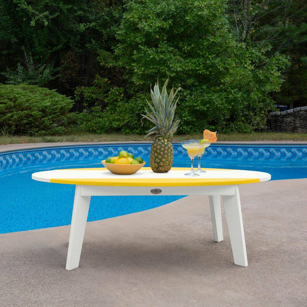 White and yellow surfboard coffee table by a pool.