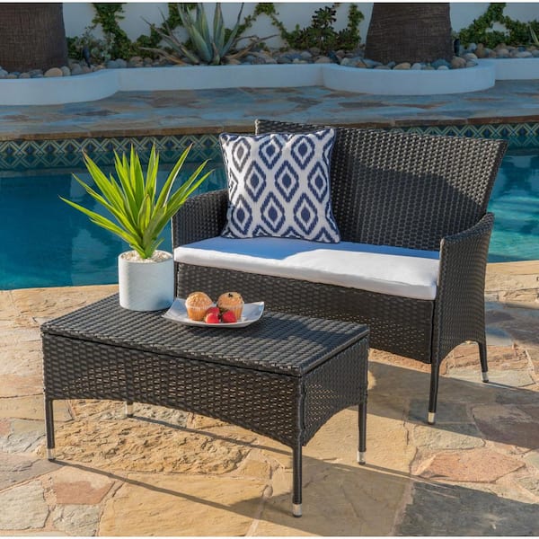 Two Small Coffee Tables And Wicker Chair With Pillow On It In