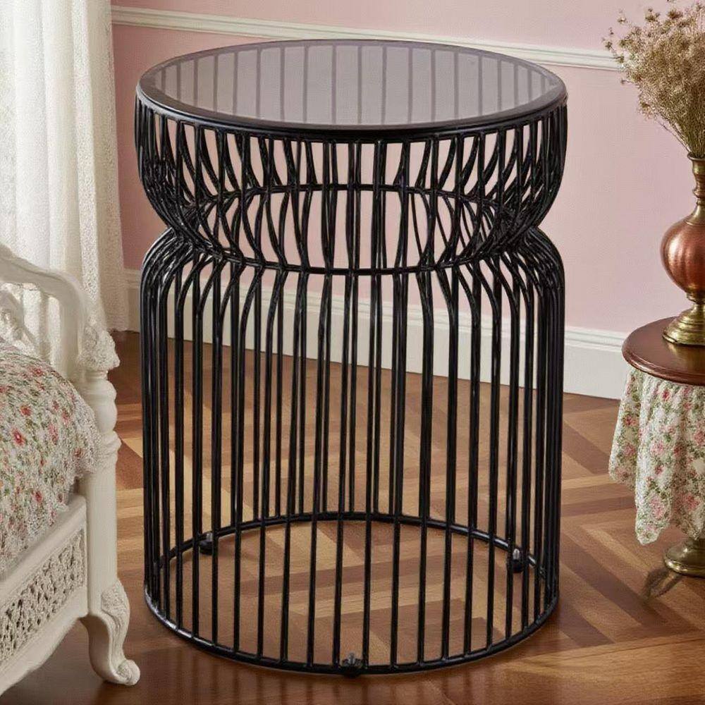 Modern round black end table with tinted glass top in a home setting.