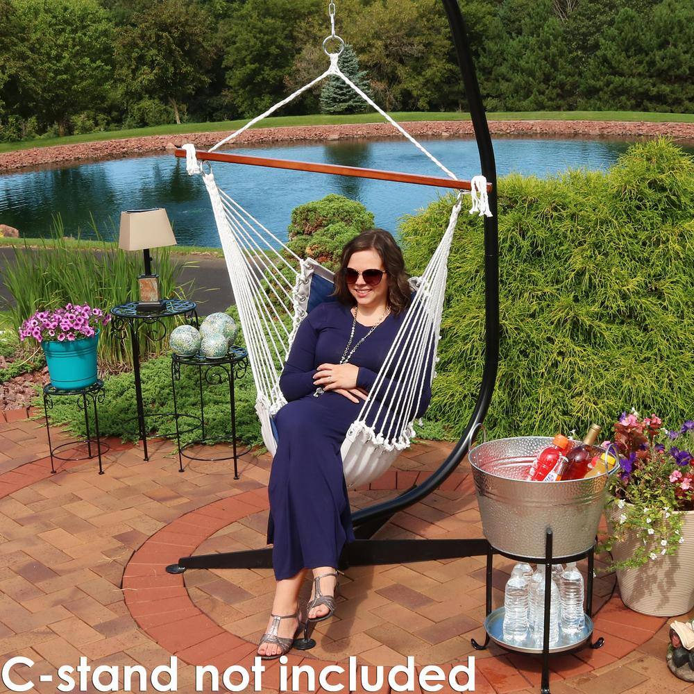 A woman sitting in a navy blue tufted Victorian hammock chair swing attached to a black C-stand.