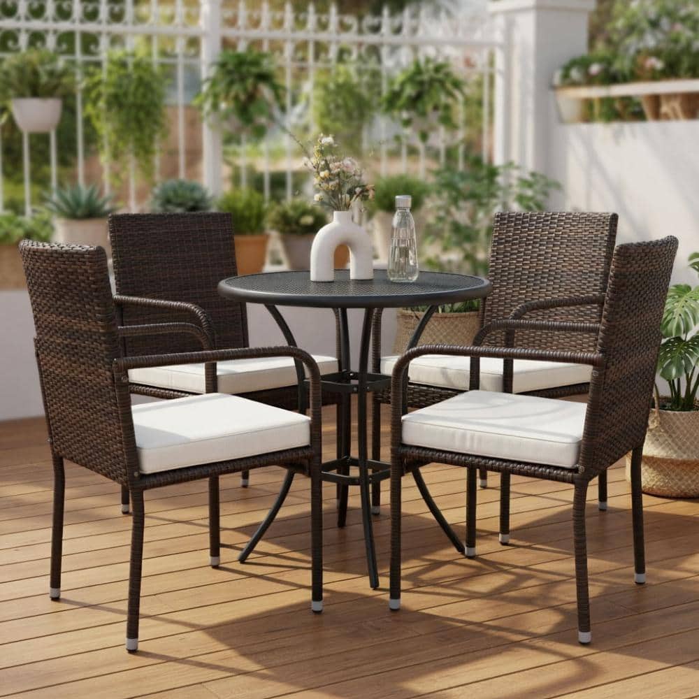 Four brown PE rattan outdoor dining chairs arranged around a round black table.