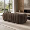 Brown round-arm tufted sofa in a room with wood paneling.