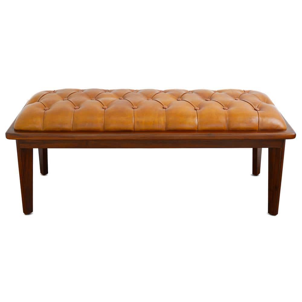 Front view of a tan leather tufted bench with teak wood legs.