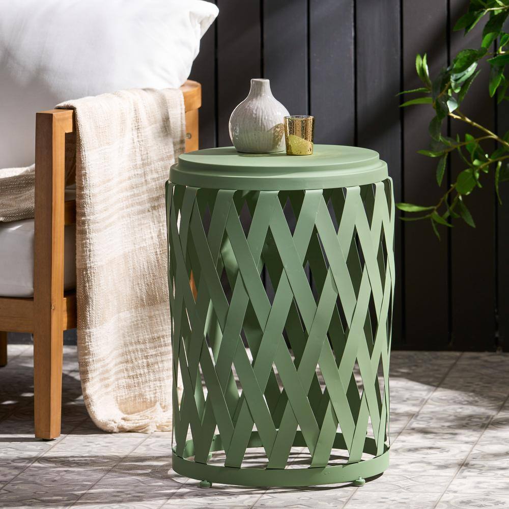 Green cylindrical side table with decor in an outdoor setting.