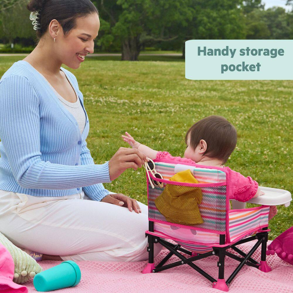 Woman helping a baby in the booster seat with storage feature.