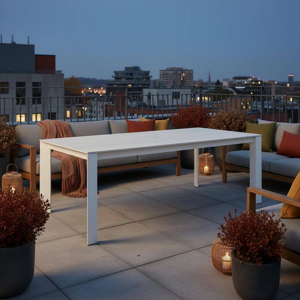 Cream rectangular aluminum outdoor dining table on a rooftop patio at dusk.