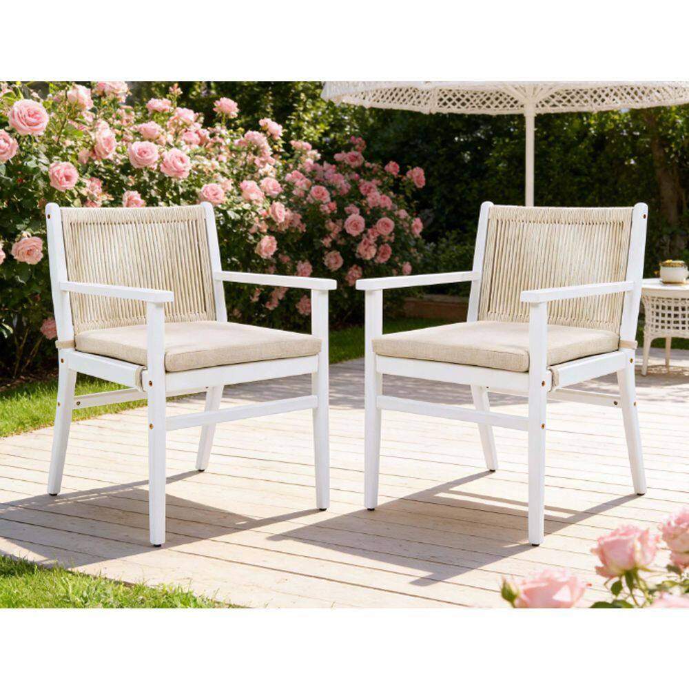 Two white acacia wood outdoor dining chairs with beige cushions in a garden setting.