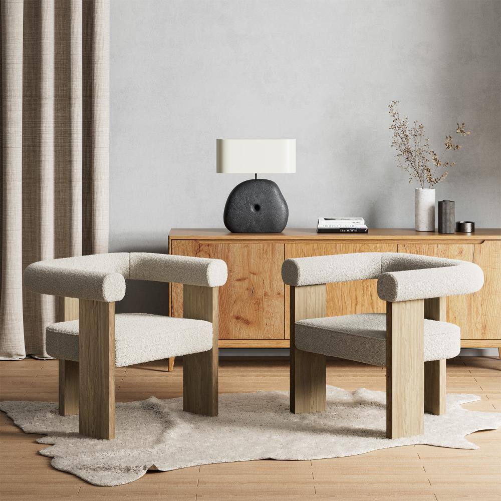 Two cream bouclé accent chairs near a wooden sideboard.