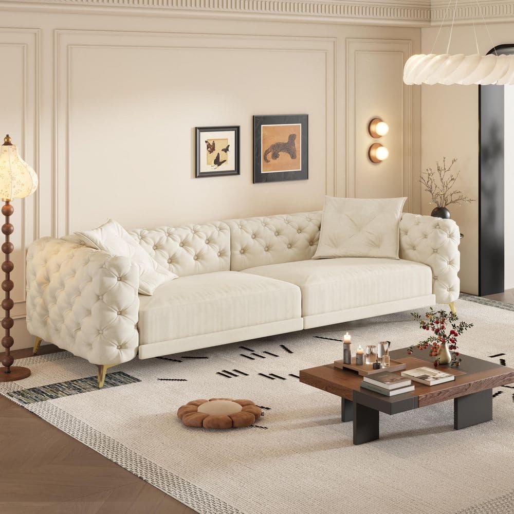 Beige/white velvet sofa with ottoman in a living room setting.