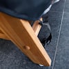 Close-up of the wooden frame and a black strap on the ottoman leg.