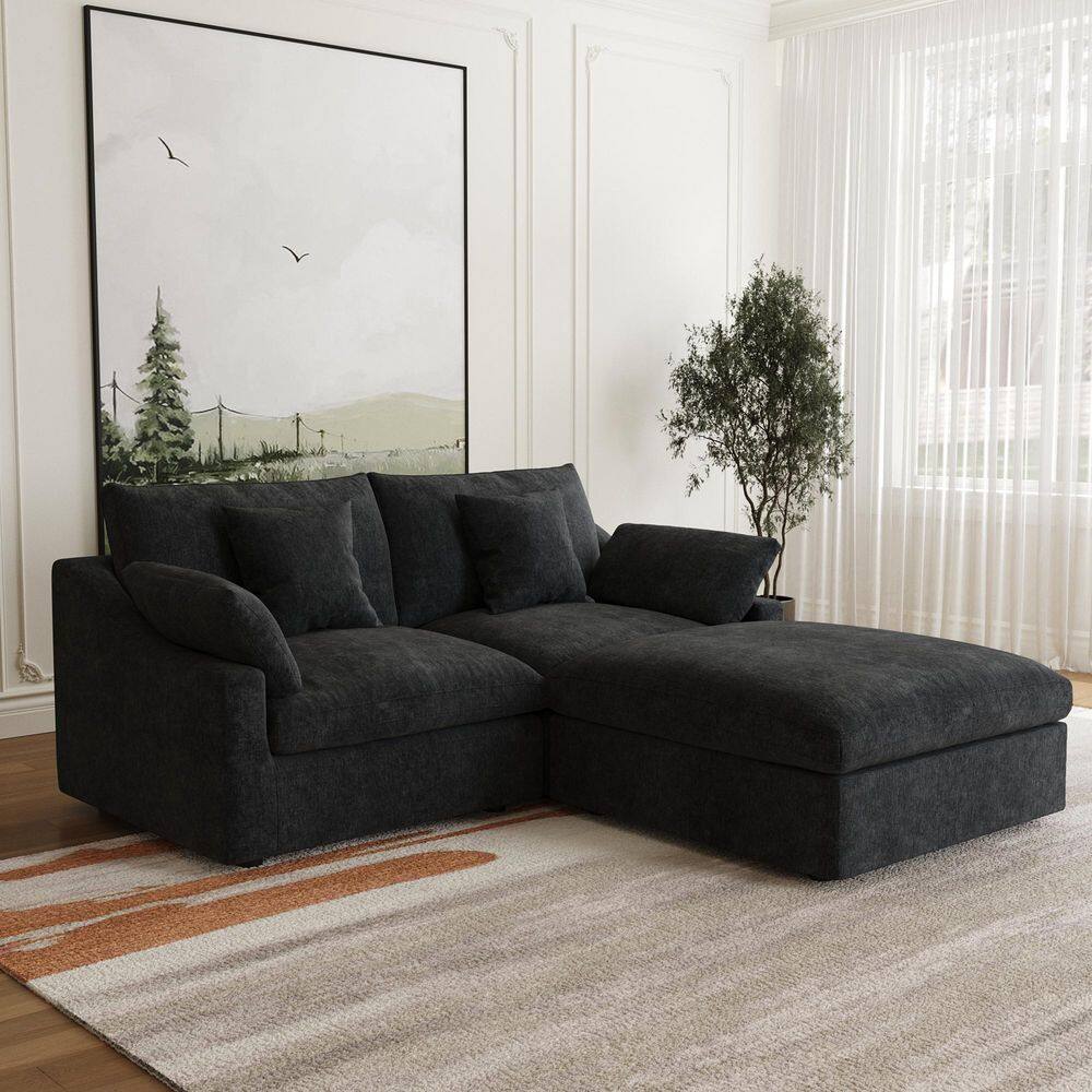 Black modular sectional sofa with ottoman in a styled living room.