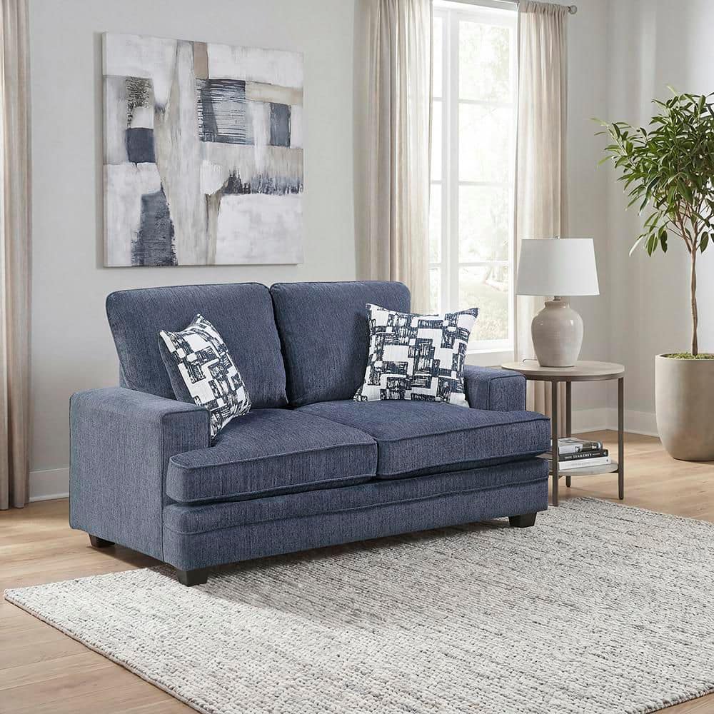 Blue sofa set placed in a living room with a rug and framed art.