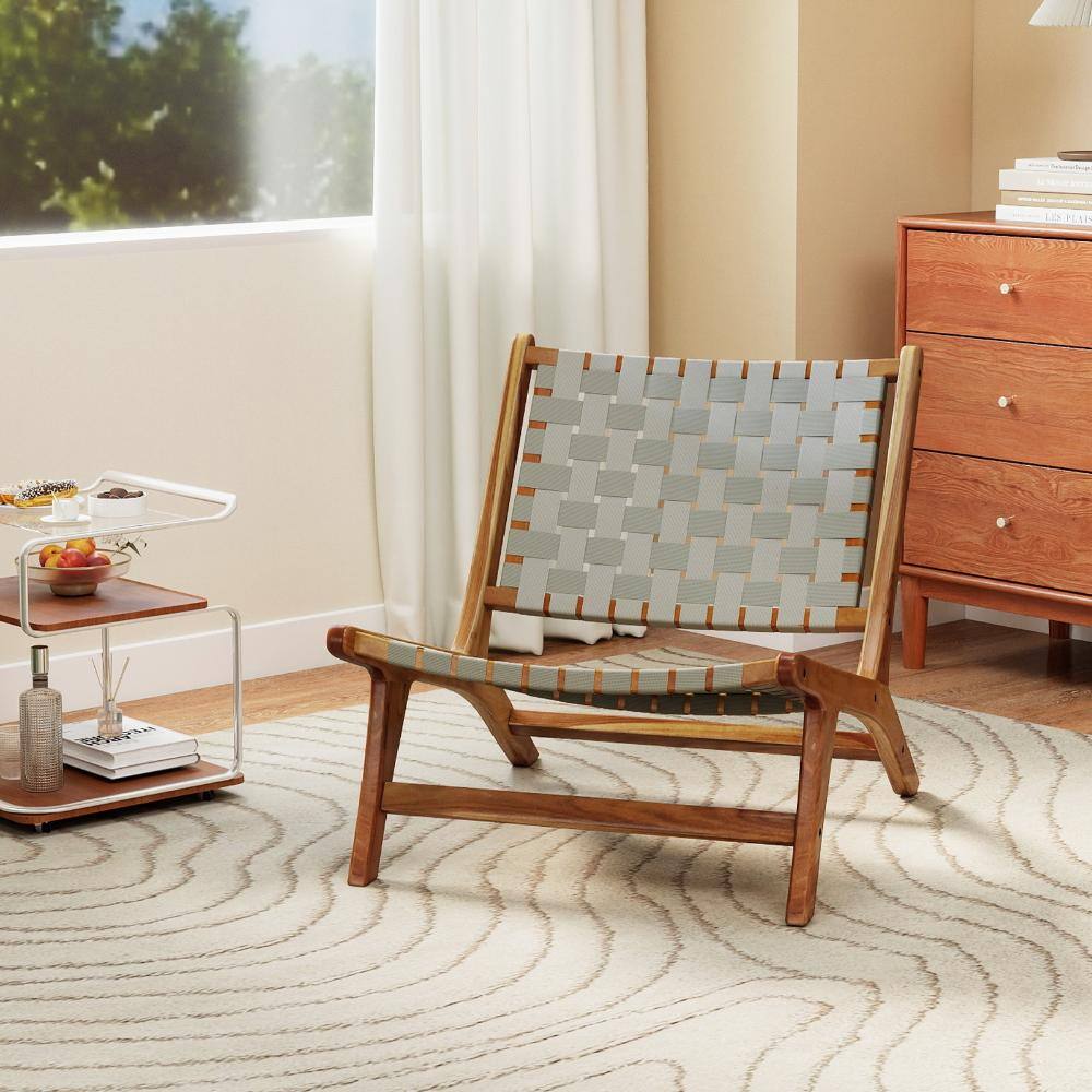 Teak wood outdoor accent chair placed in a living room setting next to wooden furniture.