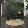 Black wooden rocking chair on a patio with a small table and rug.