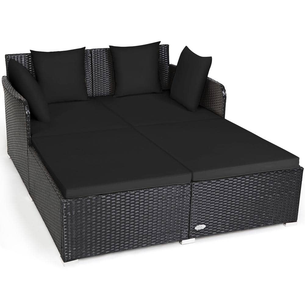 Black rattan outdoor daybed with black upholstered cushions and three black throw pillows.