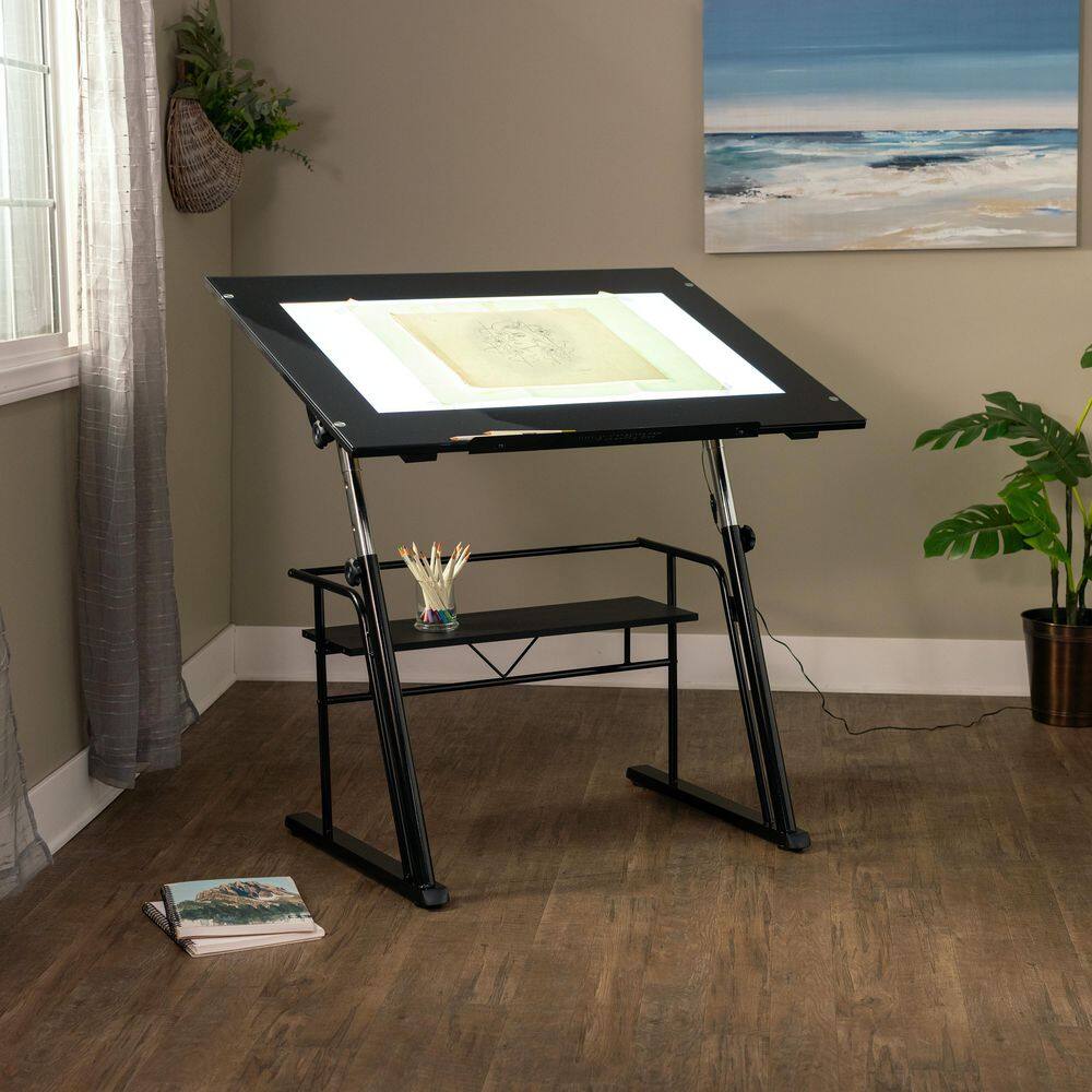 Black drawing table setup in a room with artwork.