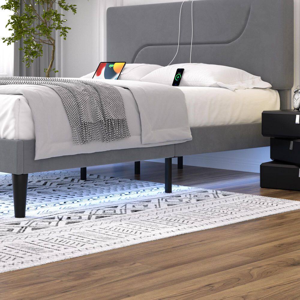 Close-up of a gray upholstered bed frame with LED under-glow lighting.