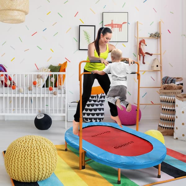 A little boy jumping on a mini-trampoline with his mother watching.