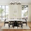 Six black dining chairs with white marble table in a bright dining room.