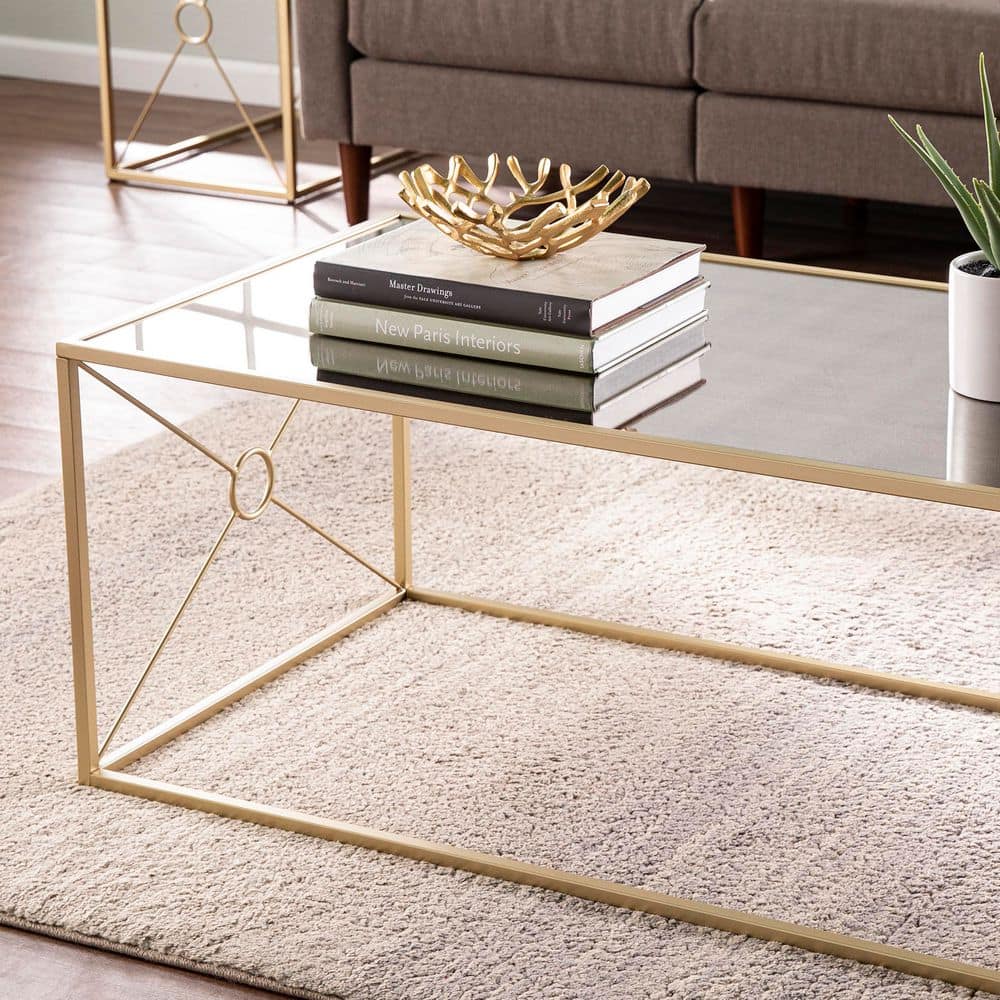 Close-up detail of the gold metal frame and mirrored top of the coffee table.