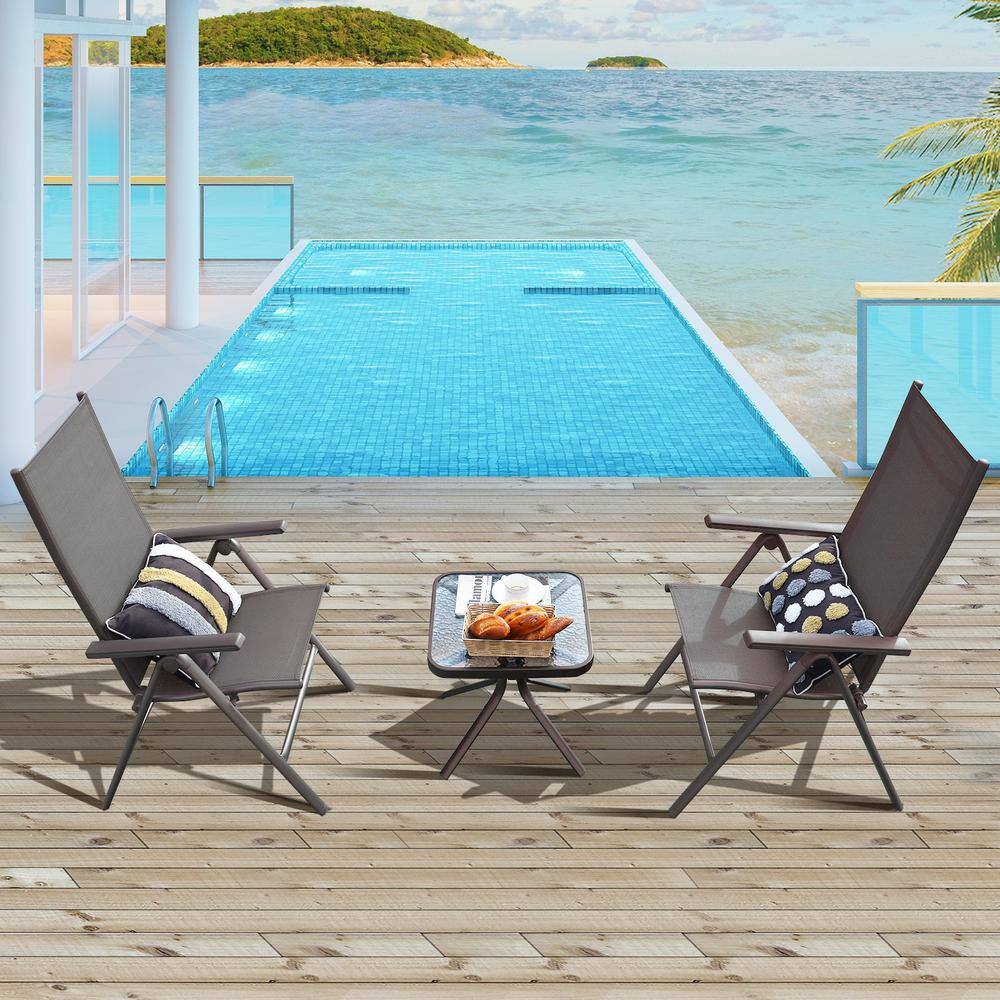 Two gray folding patio chairs with patterned pillows flanking a small black side table.