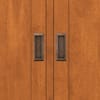 Close-up of metal handles on the teak storage cabinet doors.