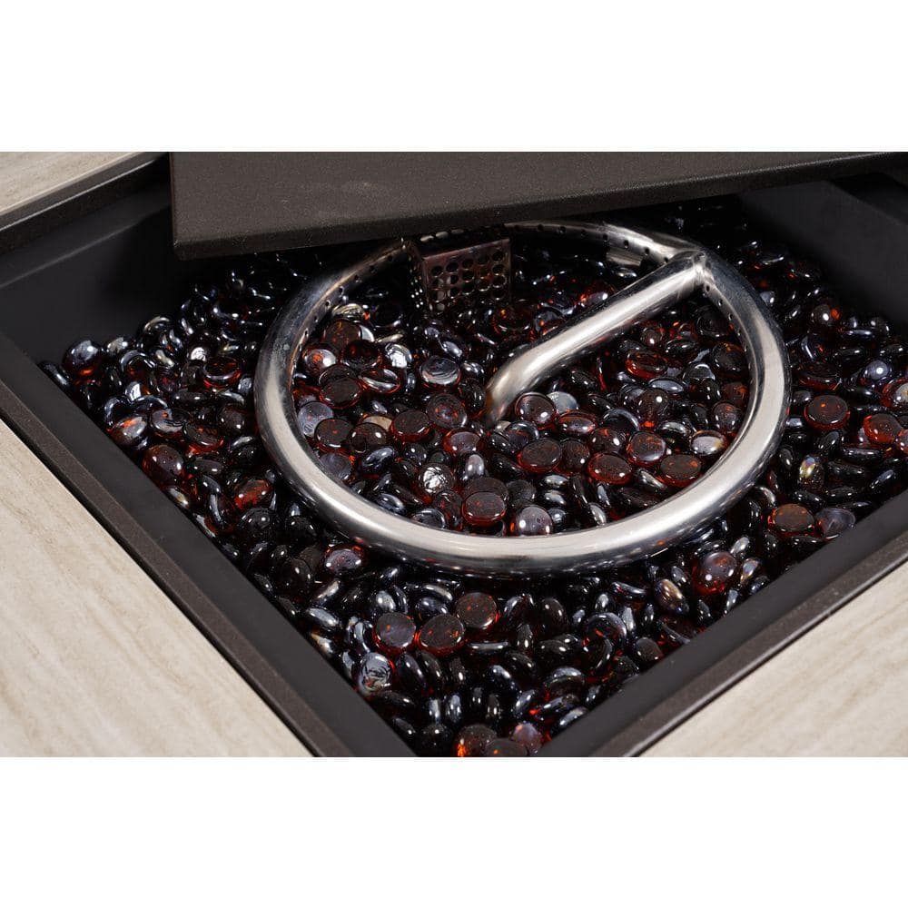 Close-up of the gas fire table's burner area filled with dark glass fire beads.