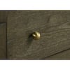 Close-up of a gold-tone knob on a dark cocoa wood dresser drawer.