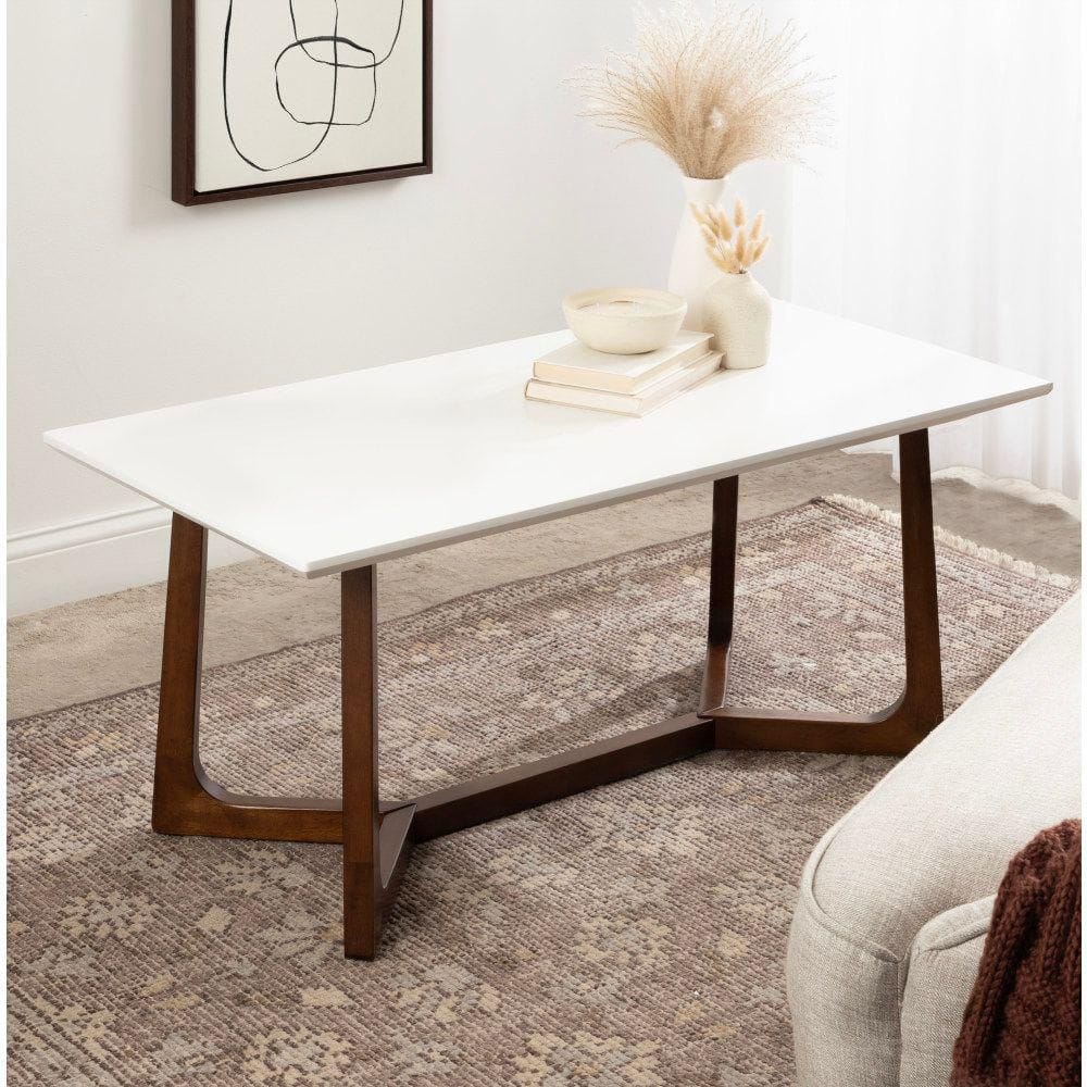 White coffee table styled with books and a vase in a living room.