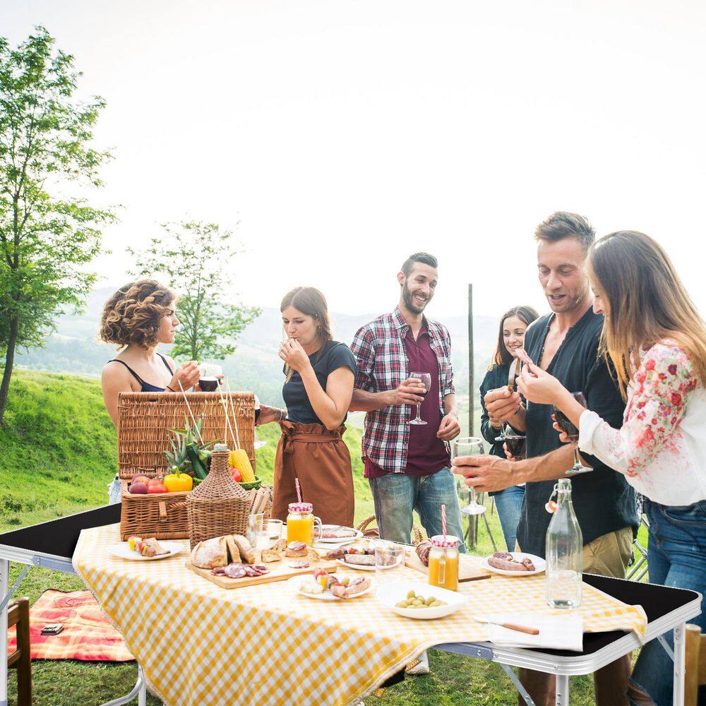 Picnic table set up outdoors with a checkered tablecloth for dining.