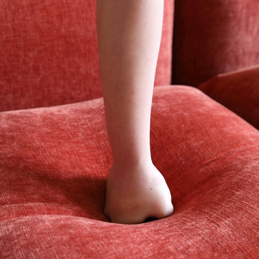 Close-up of orange chenille sofa fabric with a foot resting on it.