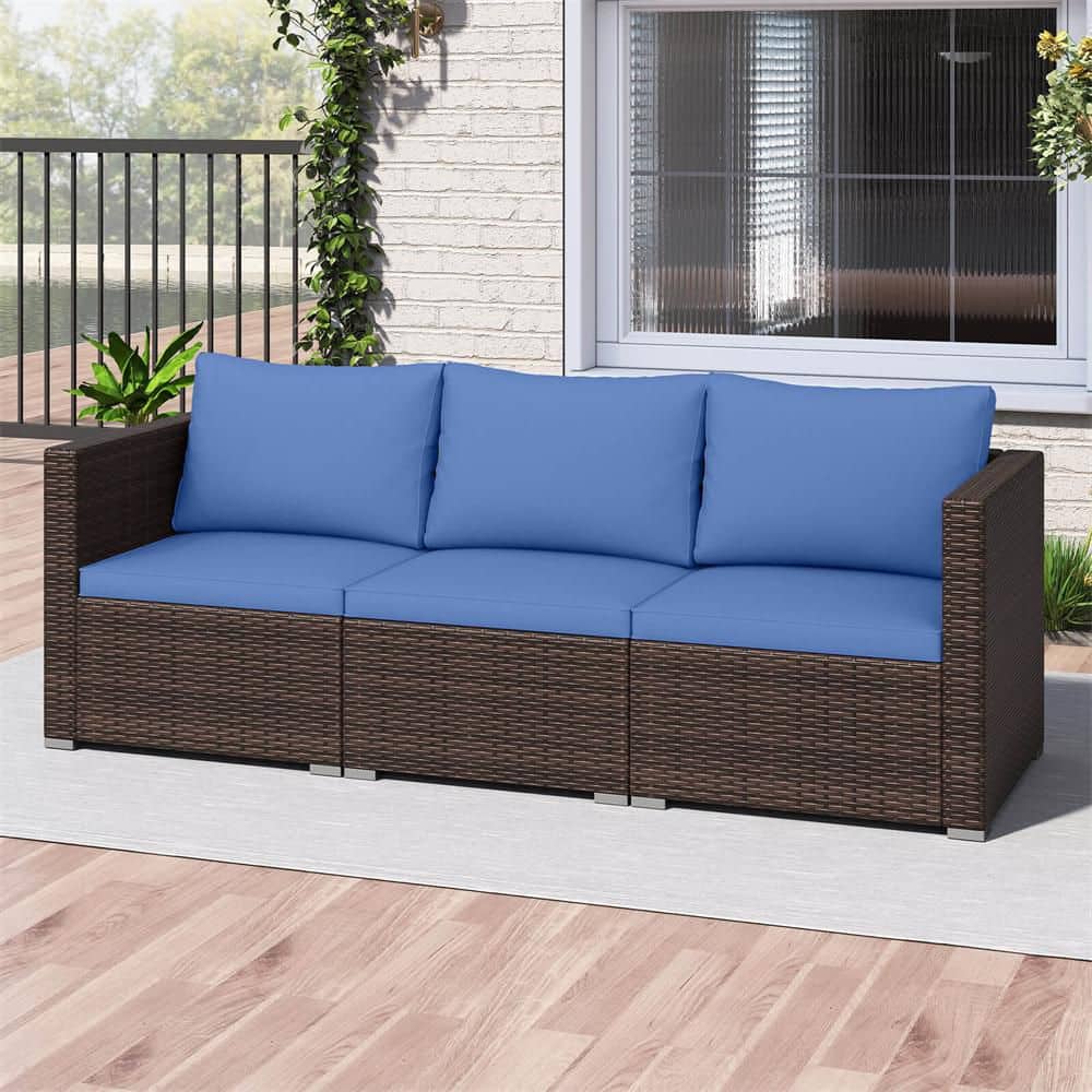 A three-seater patio sofa with dark brown wicker and navy blue cushions on a white rug.