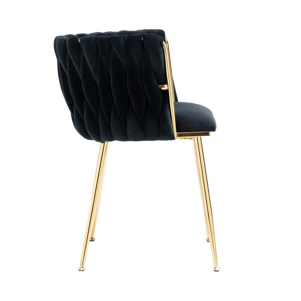 Side view of a black velvet dining chair with gold metal legs.