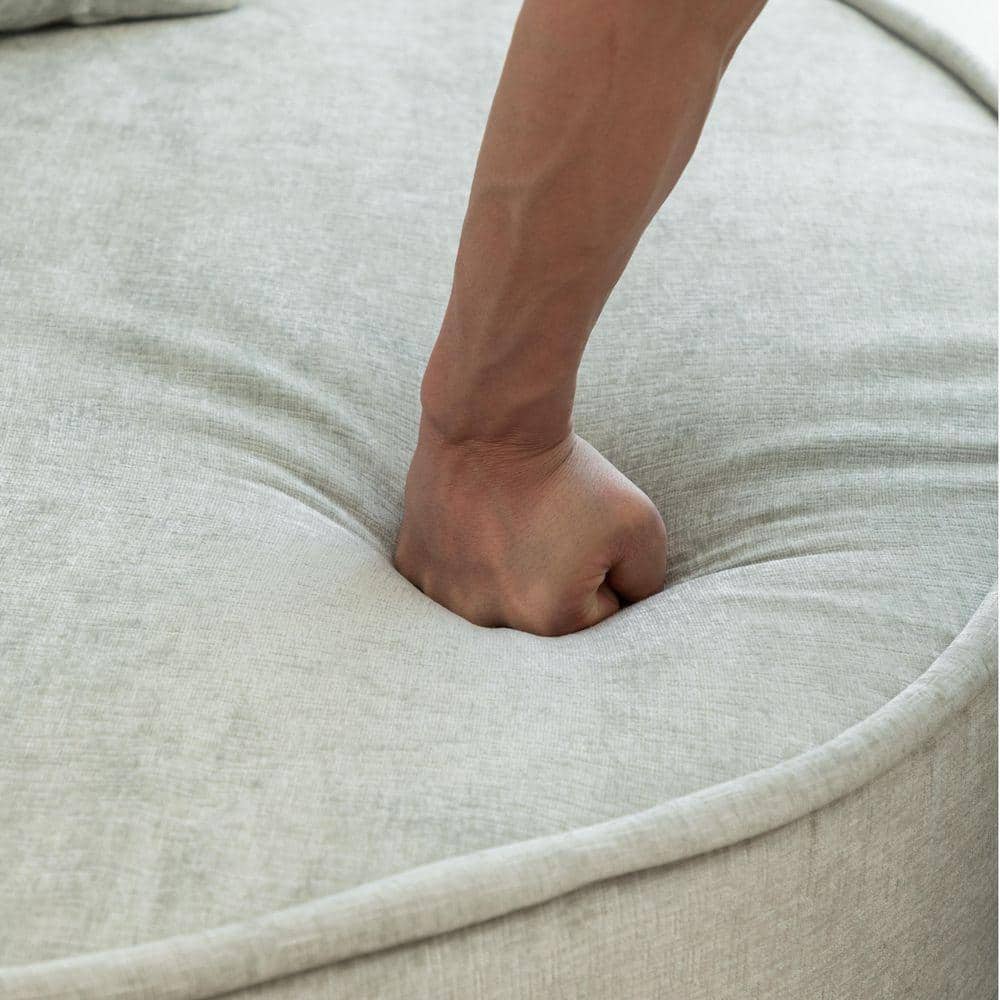 Close-up of a hand pressing into the soft grey chenille chair cushion.