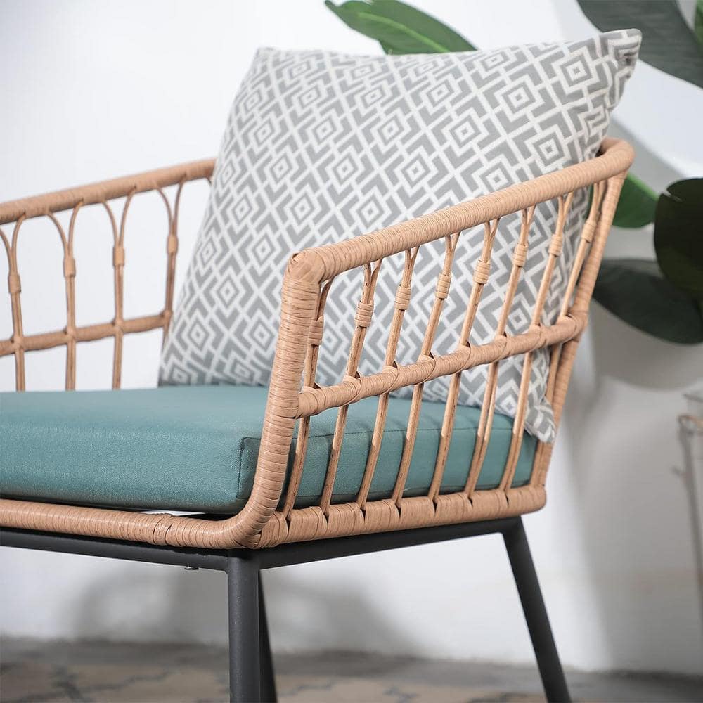 Close-up of a brown rattan chair with a teal cushion and a geometric patterned pillow.
