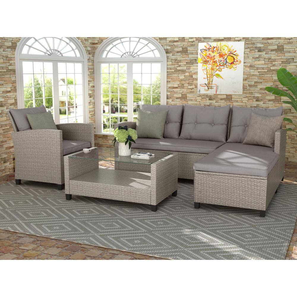 Grey wicker outdoor sectional furniture set placed on a patterned rug in a patio area.
