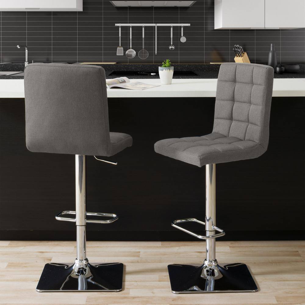Two grey tufted fabric bar stools in a modern kitchen setting.