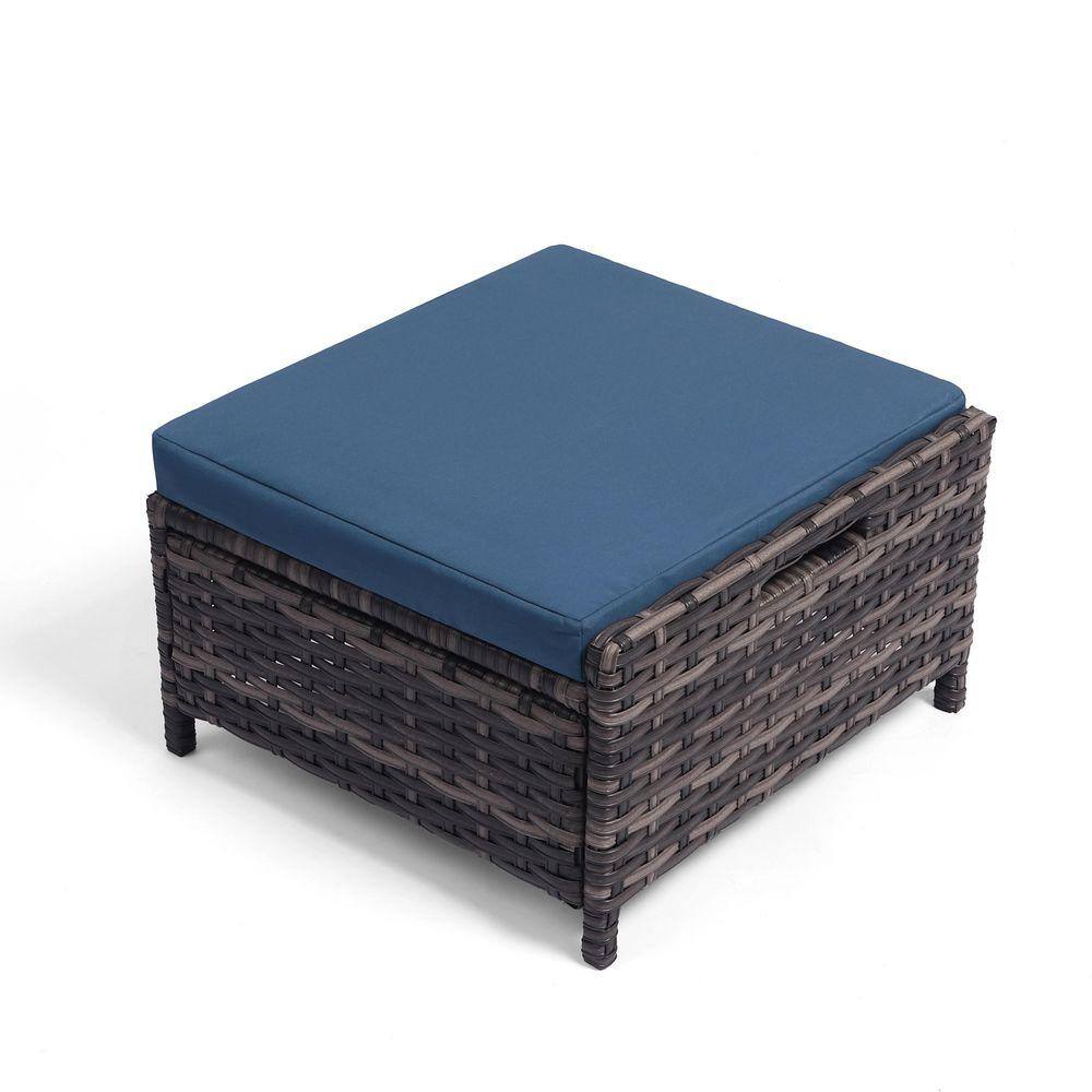A single brown rattan ottoman with a blue cushion.