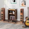 A mobile record player stand positioned between two large wooden speakers.