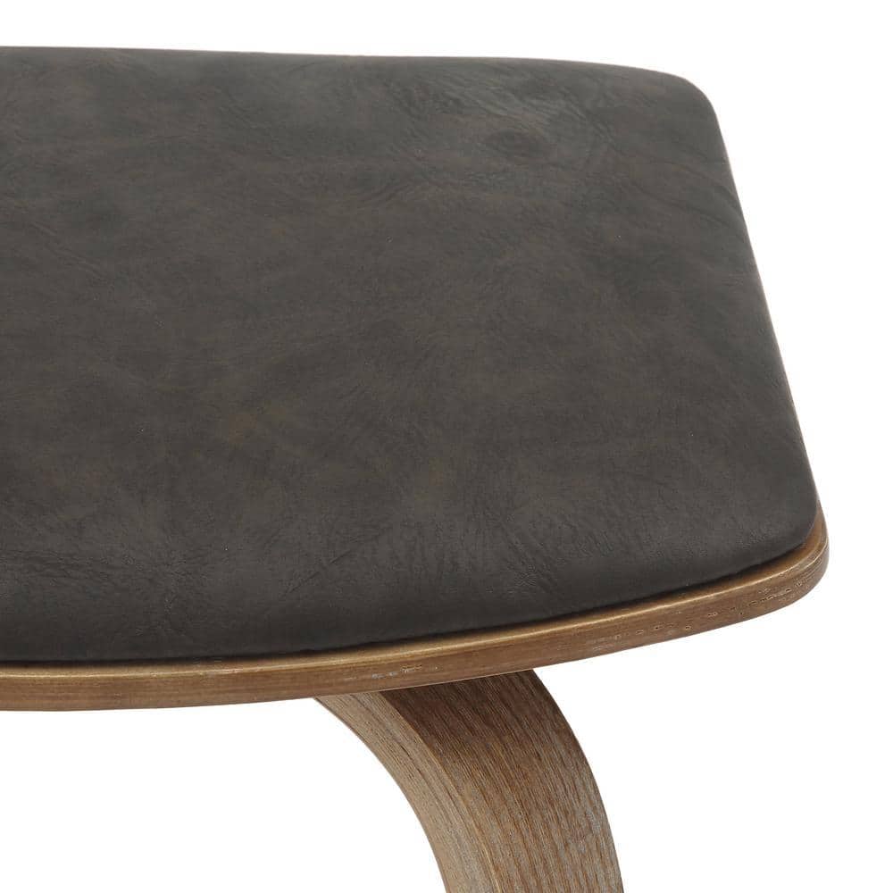Close-up texture of the dark brown leather upholstery on the stool seat.