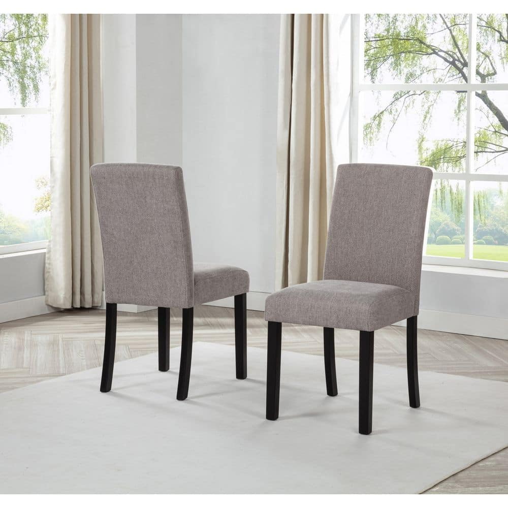 Two upholstered dining chairs with black legs in a bright room.