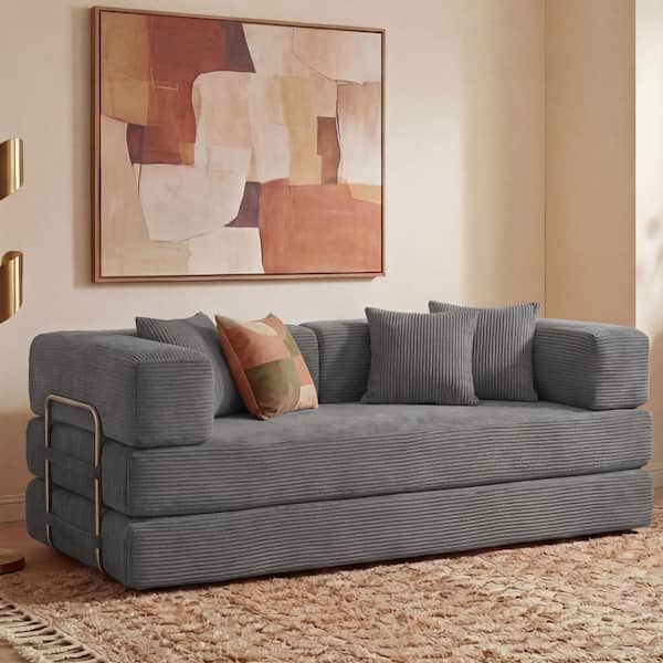 Gray corduroy sofa with pillows in a living room setting.
