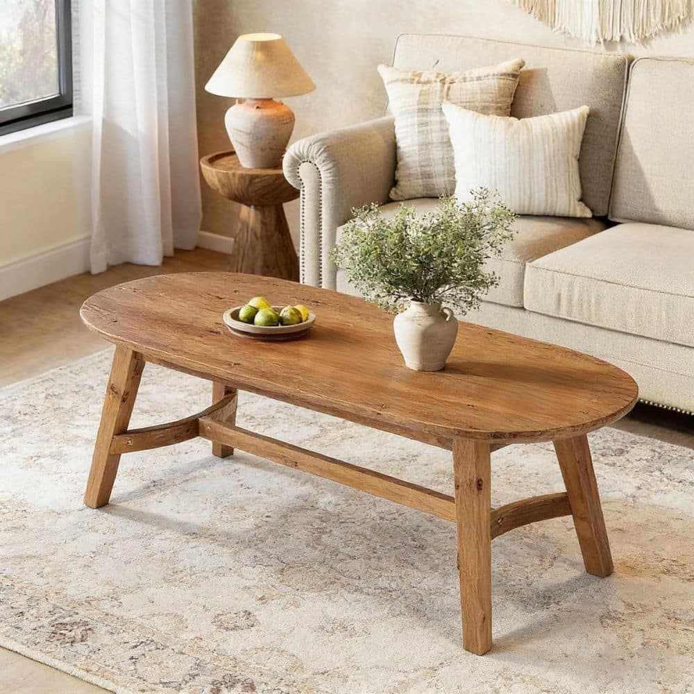 Brown oval solid wood coffee table in a living room.
