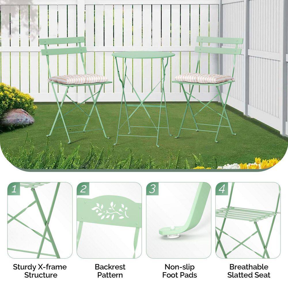 Light green metal bistro set with cushions on a lawn.