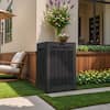 Black resin delivery box placed in a garden setting near flowers.