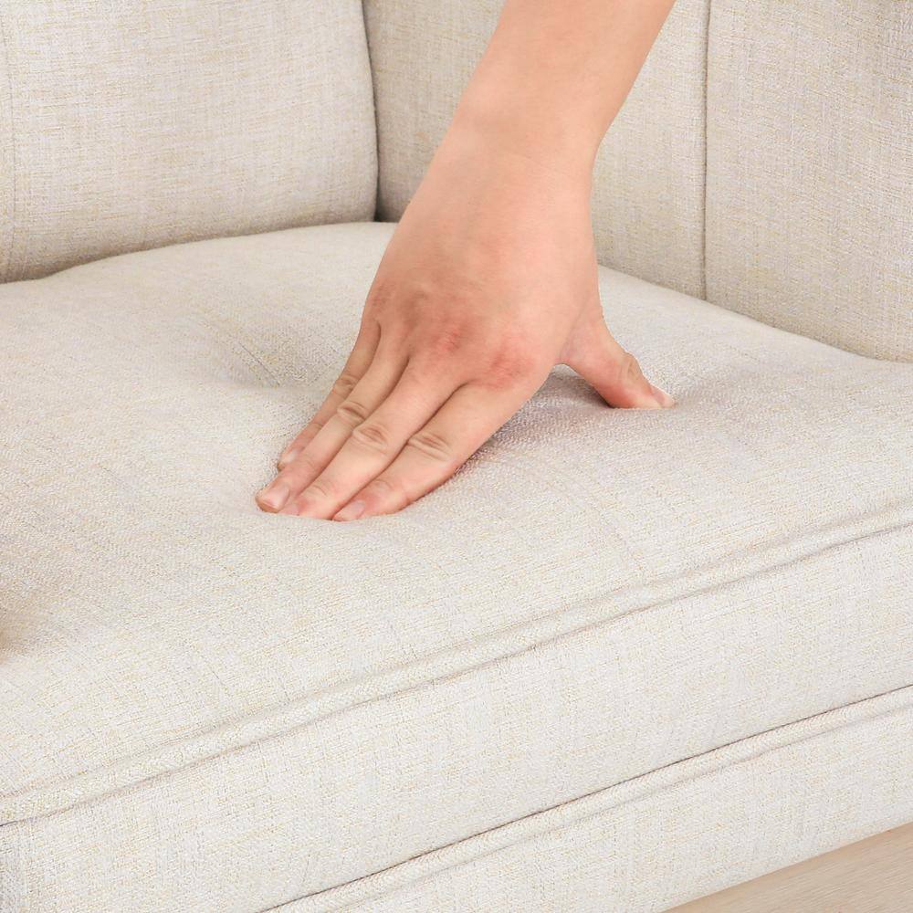 Hand touching the beige linen fabric of the bar stool seat.
